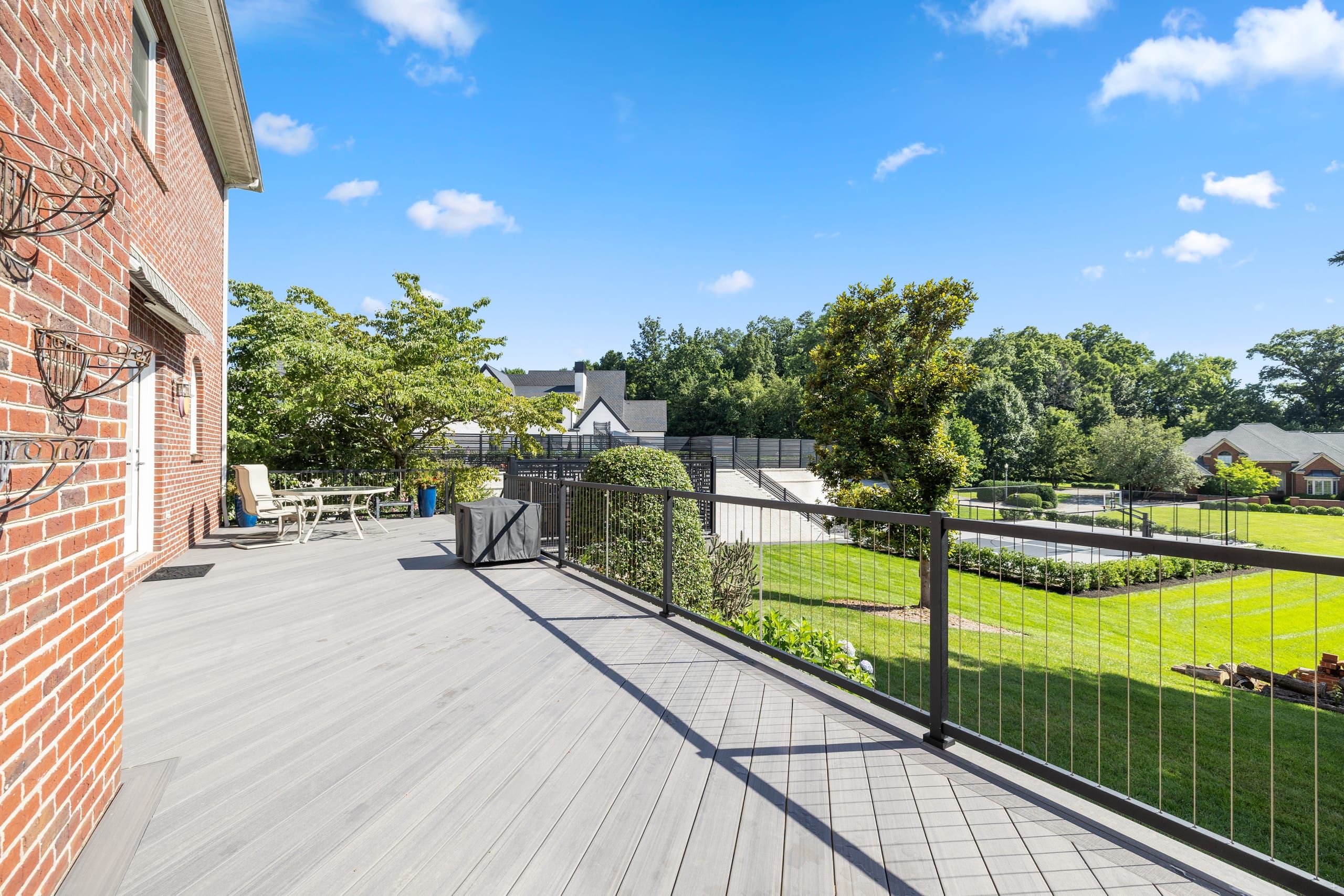 Wilshire elevated TimberTech deck in Castle Gate gray with black vertical cable railing overlooking a manicured backyard