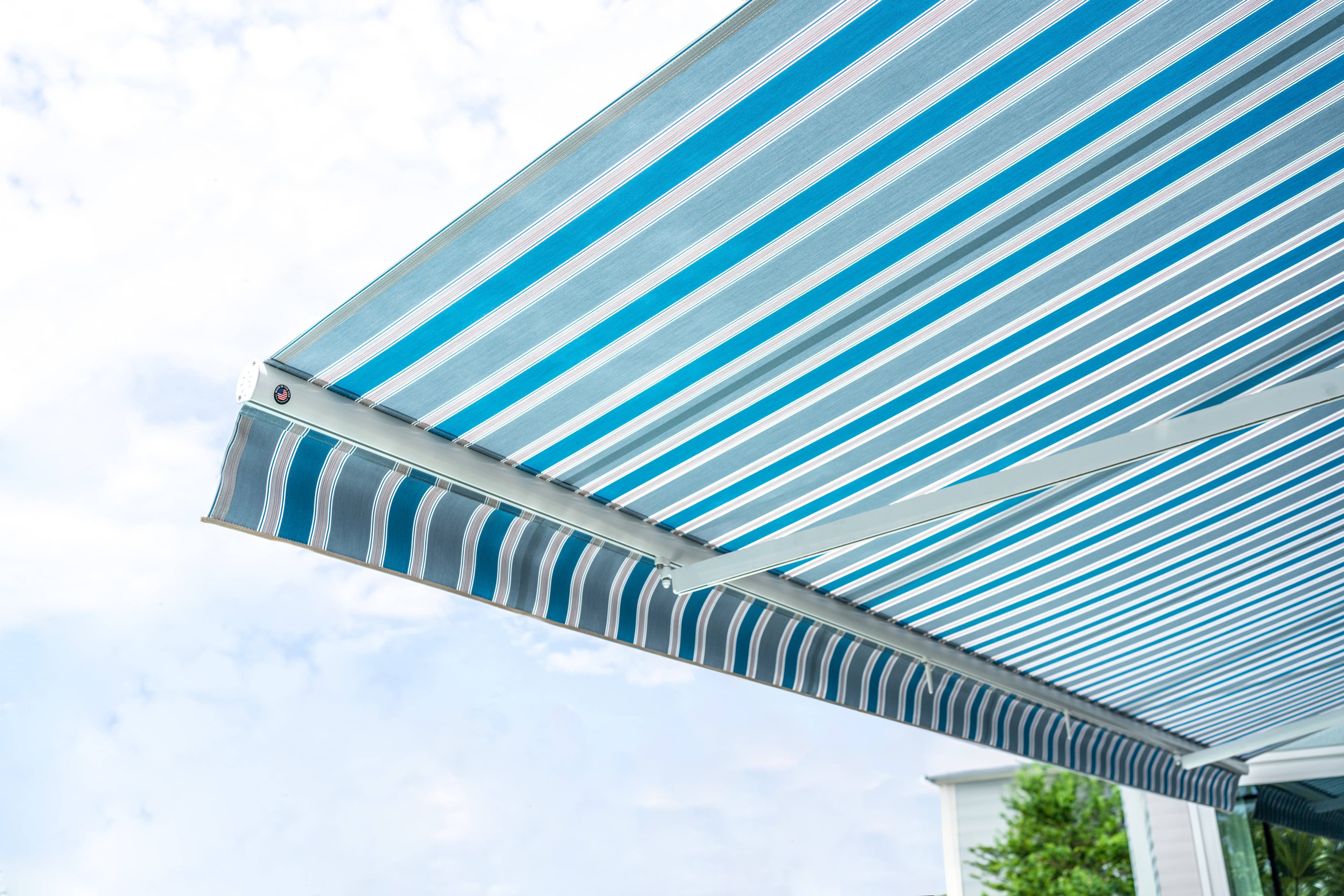 Underside view of a blue-striped retractable awning shading a sunny deck