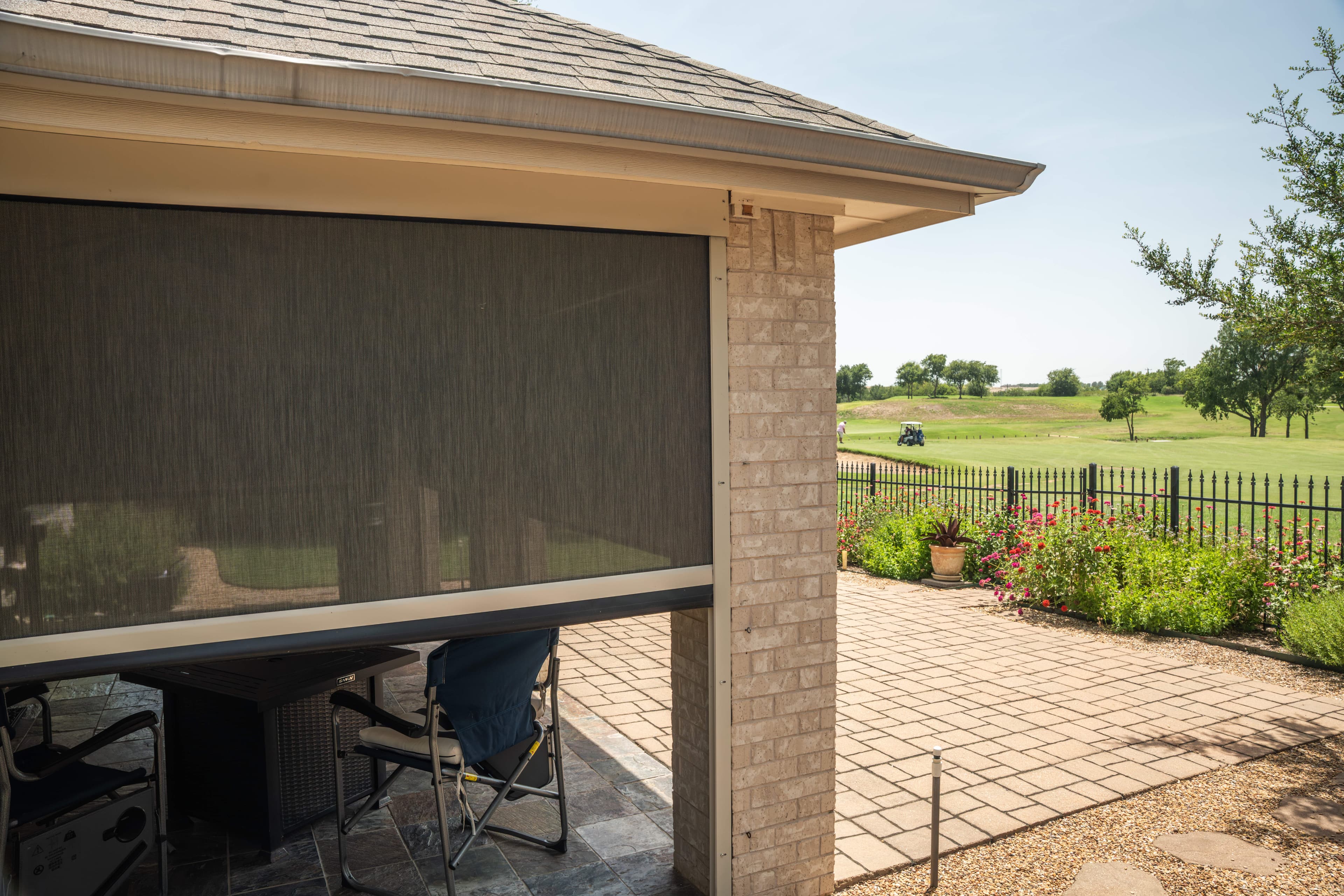 Row of SunPro motorized retractable screens with white hardware enclosing a backyard patio