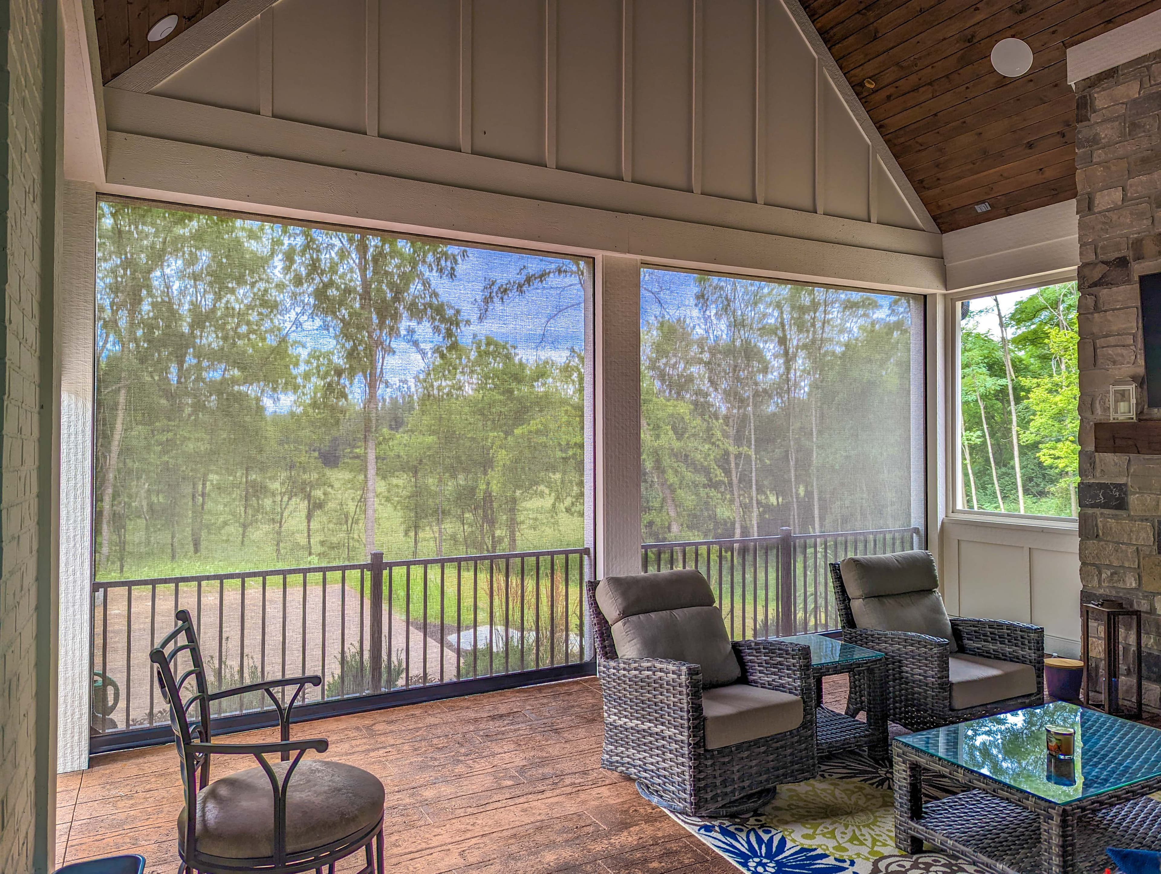 Recessed exterior screens with hidden housing enclosing a covered porch overlooking a wooded Tennessee backyard