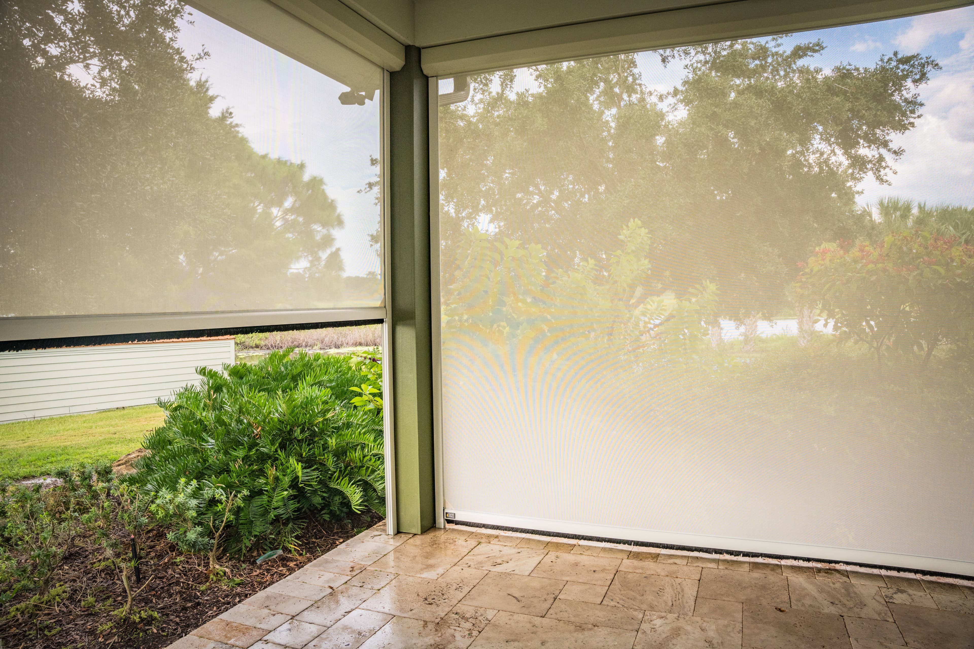 White privacy screen fabric softening the light on a covered porch with a garden view